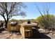 Outdoor kitchen with built in grill and bar with desert landscape in the background at 36674 N Vasari Dr, Scottsdale, AZ 85262