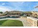 Backyard featuring a pool, turf lawn, outdoor kitchen, and fireplace area for entertainment at 6326 W Misty Willow Ln, Glendale, AZ 85310