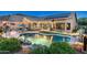 Expansive backyard with a freeform pool, patio area, outdoor kitchen, and lush landscaping at dusk at 6326 W Misty Willow Ln, Glendale, AZ 85310
