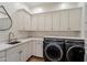 Well-organized laundry room with white cabinetry, modern washer/dryer, and marble countertops at 7002 E Aster Dr, Scottsdale, AZ 85254