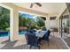 Covered patio with dining table and comfortable seating overlooking the beautiful pool and lush backyard at 7002 E Aster Dr, Scottsdale, AZ 85254