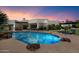 Gorgeous pool area with covered patio, outdoor kitchen, lounge chairs, and lush landscaping at sunset at 7002 E Aster Dr, Scottsdale, AZ 85254