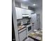 Galley kitchen featuring white cabinetry, black and brown countertops, and white appliances at 8055 E Thomas Rd # H103, Scottsdale, AZ 85251