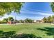 Community park featuring a grassy lawn, a playground, and several homes in the background at 9 N 87Th N Ln, Tolleson, AZ 85353