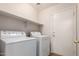 Functional laundry room featuring a washer, dryer, storage shelf, and convenient access door at 9332 W Mary Ann Dr, Peoria, AZ 85382