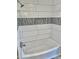 Clean, white, tiled bathtub/shower combination with decorative gray accent tiles and a built in soap niche at 13013 N 18Th St, Phoenix, AZ 85022