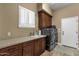 Well-lit laundry room featuring front loading washer/dryer, tile floor, granite countertops, and dark cabinets for ample storage space at 14708 E Canyoncrest Ct, Fountain Hills, AZ 85268