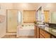 Bright bathroom featuring tub, glass enclosed shower, and palm-themed decor at 15827 S 12Th Pl, Phoenix, AZ 85048