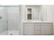 Bathroom featuring double sinks, white cabinets, a large mirror and a glass enclosed shower at 17806 W Vogel Ave, Waddell, AZ 85355