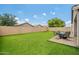 Spacious backyard featuring synthetic turf, a stone paver patio, a privacy wall, and mature trees at 19585 W Washington St, Buckeye, AZ 85326