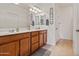 Well-lit bathroom with double sinks, wood cabinets, decorative towel racks, and neutral colored tile flooring at 19585 W Washington St, Buckeye, AZ 85326