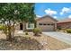 Charming home featuring a two-car garage, a driveway, desert landscaping, and a large tree at 19585 W Washington St, Buckeye, AZ 85326