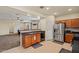 Open-concept kitchen featuring wooden cabinets, stainless steel appliances, and a breakfast bar overlooking the living area at 19585 W Washington St, Buckeye, AZ 85326