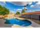 Backyard pool, rock feature, and privacy fence with palm trees in the distance at 2149 E Hermosa Vista Dr, Mesa, AZ 85213