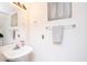 A bathroom showcasing a pedestal sink, a mirror, and a window with lace curtains, all complemented by neutral walls at 2301 E University Dr # 341, Mesa, AZ 85213
