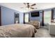 This primary bedroom features wood floors, a ceiling fan, and a seating area near the windows at 2635 W Atlanta Ave, Phoenix, AZ 85041