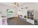 Bright bedroom with a ceiling fan, window, and white shelves filled with toys and books at 3750 E Palm St, Mesa, AZ 85215