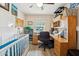 A cozy office with light wood floors, large desk, and baby bed at 5224 S Monaco Dr, Tempe, AZ 85283