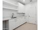 Bright laundry room with ample cabinet space, white countertops, and a utility sink for efficient chores at 5533 E Earll Dr, Phoenix, AZ 85018