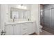 Bright bathroom featuring a double vanity with white cabinets and a glass-enclosed shower at 5537 E Earll Dr, Phoenix, AZ 85018