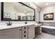 Elegant bathroom featuring a double vanity, soaking tub with tile surround, and large mirror at 5628 N Rattler Way, Litchfield Park, AZ 85340