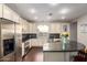 Bright kitchen features stainless steel appliances, white cabinets, dark granite counters and a functional island at 5628 N Rattler Way, Litchfield Park, AZ 85340