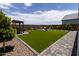 A backyard with a well-manicured lawn, a stone pathway, and a covered patio area at 5633 N 206Th Ave, Buckeye, AZ 85396