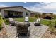 Landscaped backyard featuring artificial turf, a stone patio, fire pit, and comfortable seating at 5633 N 206Th Ave, Buckeye, AZ 85396