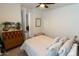Bright bedroom features a ceiling fan, a cozy bed with a cushioned bench and an open door to a bathroom at 5633 N 206Th Ave, Buckeye, AZ 85396