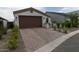 Charming single-Gathering home showcasing a brown garage door and brick paver driveway, surrounded by well-maintained landscaping at 5633 N 206Th Ave, Buckeye, AZ 85396