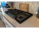 Close-up of a modern stovetop featuring sleek design and stainless-steel knobs, complemented by clean countertops at 5633 N 206Th Ave, Buckeye, AZ 85396
