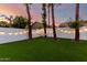 Green backyard with artificial turf, mature trees, hammock, and string lights at 6518 W Louise Dr, Glendale, AZ 85310