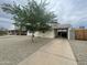 A single-story home boasts a covered parking area, a tree, and minimal landscaping, combining practicality with a touch of nature at 6832 W Vogel Ave, Peoria, AZ 85345