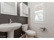 Stylish half bathroom featuring a pedestal sink, decorative mirror, and window with white shutters at 1857 W 22Nd Ave, Apache Junction, AZ 85120