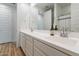 Bright bathroom features double vanity with white countertop and cabinets, framed by a large mirror and wood-look flooring at 21303 E Estrella Rd, Queen Creek, AZ 85142