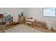 Bright playroom features wooden shelves, a table and chair set, plus a neutral patterned rug over wood floors at 21303 E Estrella Rd, Queen Creek, AZ 85142