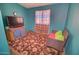 This small room features a patterned carpet, a window with curtains, and a comfortable chair for relaxing at 43384 W Padilla Rd, Maricopa, AZ 85138