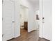 Bright hallway featuring wood-look tile floors, white doors, and a view into a half-bathroom at 46484 W Lander Ln, Maricopa, AZ 85139