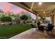 Inviting covered back patio with string lights, green lawn, and cozy outdoor seating at dusk at 5123 S Mariposa Dr, Gilbert, AZ 85298