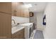 Well-lit laundry room features sink, washer, dryer, skylight, modern cabinetry, and stainless steel refrigerator at 5438 E Lupine Ave, Scottsdale, AZ 85254