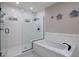 Modern bathroom with a walk-in shower, soaking tub, white tiling, and matte black hardware at 5926 E Hartford Ave, Scottsdale, AZ 85254