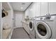 Well-lit laundry room features modern washer and dryer, sink, white cabinets, and convenient bench at 5926 E Hartford Ave, Scottsdale, AZ 85254