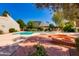 Community pool with mature landscaping, lounge chairs, and a built-in brick fire pit at 6 E Manzanita Dr, Phoenix, AZ 85020