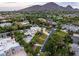 Stunning aerial view of a luxury home with a pool, solar panels, lush landscaping, and mountain views at 6611 N 64Th Pl, Paradise Valley, AZ 85253