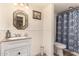 Well-lit bathroom boasts a vanity, framed mirror, wainscoting, and shower with patterned curtain at 7604 N 46Th Ave, Glendale, AZ 85301