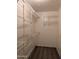 Walk-in closet with white wire shelving on the walls and dark wood-look flooring at 10399 E Hillery Dr, Scottsdale, AZ 85255