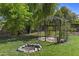 Lush backyard featuring a charming gazebo, mature trees, and a unique rock fire pit for outdoor enjoyment at 1135 W Sea Fog Dr, Gilbert, AZ 85233