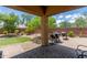 Inviting backyard featuring a covered patio, brick wall, lush landscaping, and well-maintained pavers for outdoor enjoyment at 13720 N 148Th Dr, Surprise, AZ 85379