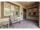 Inviting covered front porch with stone accents, outdoor seating, and a decorative front door at 13720 N 148Th Dr, Surprise, AZ 85379