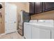 Convenient laundry room with stainless steel appliances, cabinetry, and white door at 13720 N 148Th Dr, Surprise, AZ 85379